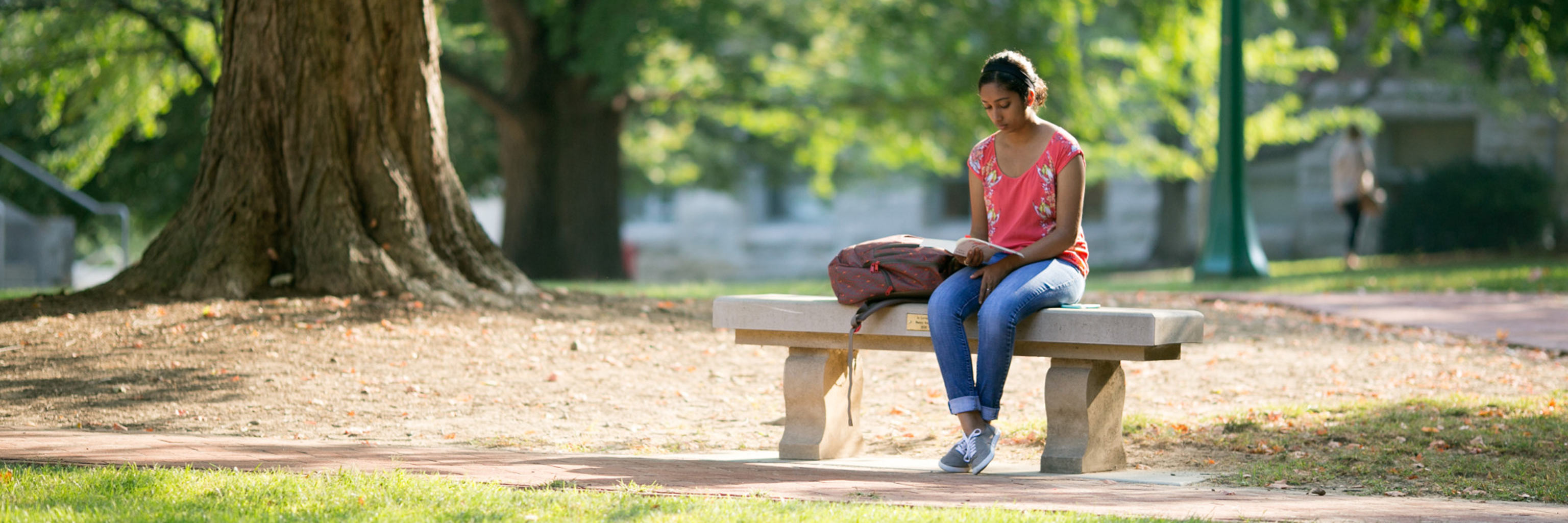A girl sitting on a bench reading